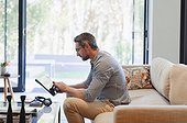 Man using digital tablet on living room sofa