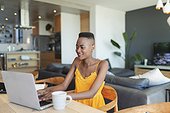 Young woman using laptop, working from home at dining table