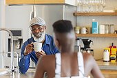 Father and daughter talking and drinking coffee in kitchen