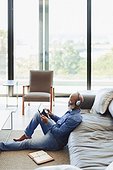 Man with headphones using digital tablet on living room floor