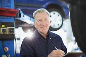 Portrait confident male mechanic with clipboard in auto repair shop