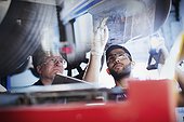 Male mechanics working under car in auto repair shop