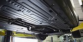Undercarriage of car on hydraulic lift in auto repair shop