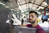Focused male mechanic using digital tablet in auto repair shop