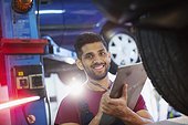 Portrait confident, smiling male mechanic with clipboard in auto repair shop