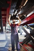Male mechanic working under car in auto repair shop