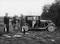 Roger-Viollet | 158833 | Wild rabbit hunting. Men loading the game in the trunk of a car. France, 1934. | © Jacques Boyer / Roger-Viollet