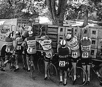 Roger-Viollet | 208501 | Racing cyclists getting fresh supplies in the Tour de France on 1964 (stage Toulon-Montpelier). From left to right : Pierre Everaert, Jean Milesi, Camille Vyncke, Rudi Altig, Guy Epaud, Paul Vermeulen, Willy Monty and Guillaume Van Tongerloo. | © Roger-Viollet / Roger-Viollet
