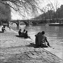Roger-Viollet | 300074 | Détente au bord de la Seine, quai du Louvre, près du Pont Neuf. Paris, années 1955-1960. | © Oswald Perrelle / Roger-Viollet