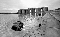 Roger-Viollet | 325075 | Fiat 500 in the water. In the background, the Arches of the lake, designed by Ricardo Bofill, Spanish architect. Saint-Quentin-en-Yvelines (France), 1984. | © Roger-Viollet / Roger-Viollet