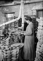 Roger-Viollet | 325816 | World War I. Woman working at producing trench clogs. Soles pumiced by grindstone. | © Jacques Boyer / Roger-Viollet