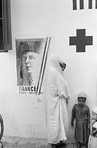 Roger-Viollet | 346683 | Dans la Mitidja, entrée de l'infirmerie. Campagne électorale pour le référendum pour la constitution de la Ve République Française. Algérie, 1958. Photographie de Jean Marquis (1926-2019). | © Jean Marquis / Roger-Viollet