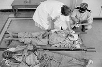 Roger-Viollet | 407104 | Infirmary. Military doctor treating two workers who stepped on a mine crossing the Morice Line (border between Algeria and Tunisia). Ouenza (Algeria), 1958. Photograph by Jean Marquis (1926-2019). | © Jean Marquis / Roger-Viollet