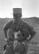 Roger-Viollet | 427332 | Algerian War of Independence. Cherchell Infantry Military School. Lieutenant instructor Meniole D'Hauthuile with a young boy from the area. Algeria, August 1960. | © Jean-Pierre Laffont / Roger-Viollet