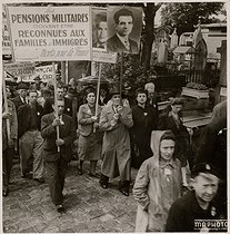 Roger-Viollet | 435510 | Demonstration for the payment of military pensions for the families of immigrants who died for France. Man holding a portrait of Missak Manouchian (1906-1944), Armenian poet and resistance fighter who died executed by the German army. | © Archives Manouchian / Roger-Viollet