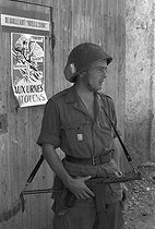 Roger-Viollet | 461233 | Algerian War of Independence. Cherchell Infantry Military School. A military cadet in front of a propaganda poster for the referendum. Algeria, October 1960. | © Jean-Pierre Laffont / Roger-Viollet