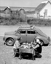 Roger-Viollet | 473011 | Couple attablé devant une 4CV. Camargue (France), 1954. | © Roger-Viollet / Roger-Viollet