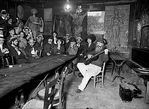Roger-Viollet | 521533 | The  Lapin Agile  cabaret. Meeting of Parisian artists among whom Poulbot, Dufy, Barrère, Neumont, Roubille, listening to old Frédé (playing the guitar). Paris, circa 1905. | © Albert Harlingue / Roger-Viollet