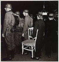 Roger-Viollet | 558555 | On the underground platform, German soldiers and a man carrying a chair, underground station, direction  porte des Lilas . Paris (VIIIth arrondissement), 1943. Photograph by Roger Schall (1904-1995). Paris, musée Carnavalet. | © Roger Schall / Musée Carnavalet / Roger-Viollet