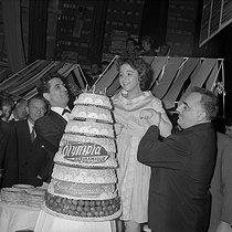 Roger-Viollet | 633060 | Brenda Lee, young American singer blowing the candles of a birthday cake celebrating the 5th anniversary of the Olympia. On her sides : Gilbert Bécaud and Bruno Coquatrix. Paris, Olympia, February 1959. | © Studio Lipnitzki / Roger-Viollet