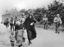 Roger-Viollet | 693268 | World War II. Front of Normandy. US rangers and French civilians walking on a road. | © Roger-Viollet / Roger-Viollet