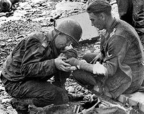 Roger-Viollet | 705128 | Guerre 1939-1945. Débarquement en Normandie. Médecin américain soignant un prisonnier allemand à Omaha Beach (Calvados), 6 juin 1944. | © Roger-Viollet / Roger-Viollet