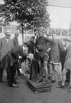 Roger-Viollet | 929861 | Finish of the 1912 Tour de France. Weighing a racing cyclist. | © Maurice-Louis Branger / Roger-Viollet