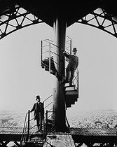 Roger-Viollet | 930428 | Gustave Eiffel (1832-1923), French engineer and builder, wearing a top hat, on the top of the Tower, with his son-in-law and colleague, Mr Salles, 1889. | © Neurdein / Roger-Viollet