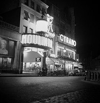 Roger-Viollet | 1030067 | Montmartre at night. View of the Moulin Rouge from the place Blanche. Paris (XVIIIth and IXth arrondissements), August 1953. | © Roger-Viollet / Roger-Viollet