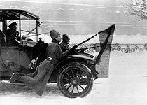 Roger-Viollet | 1060031 | 1917 Russian Revolution. Soldiers on the mud flaps of a car, holding red flags fixed to their bayonets, during the March days in Petrograd. | © Roger-Viollet / Roger-Viollet