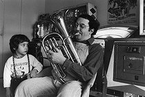 Roger-Viollet | 1376586 | Coluche (1944-1986), French humorist and actor, with his son Romain Colucci (born in in 1972), at their home rue des Plantes. Paris (XIVth arrondissement), on December 8, 1975. Photograph by André Perlstein (born in 1942). | © André Perlstein / Roger-Viollet